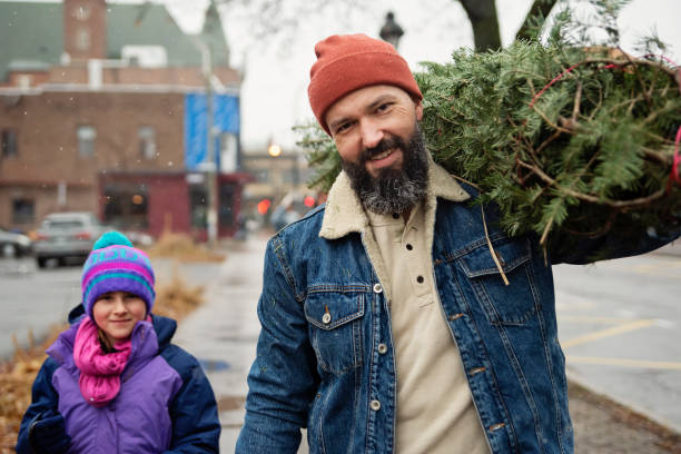 Urban father and daughter bringing home a Christmas tree.