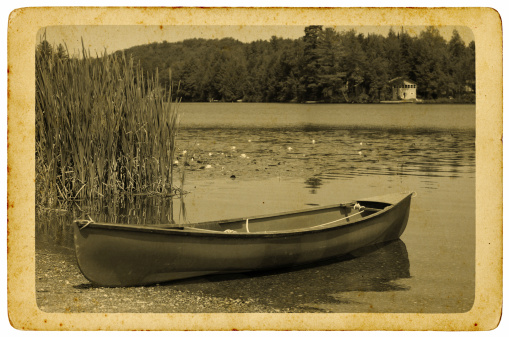 a canoe aside a lake with old postcard/photograph effect