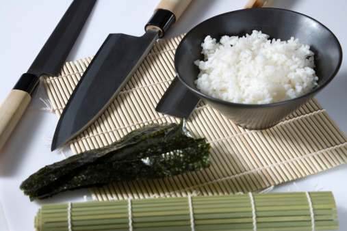 A Selection of Sushi Knives With A Bowl Of Sushi Rice & Dried Seaweed.