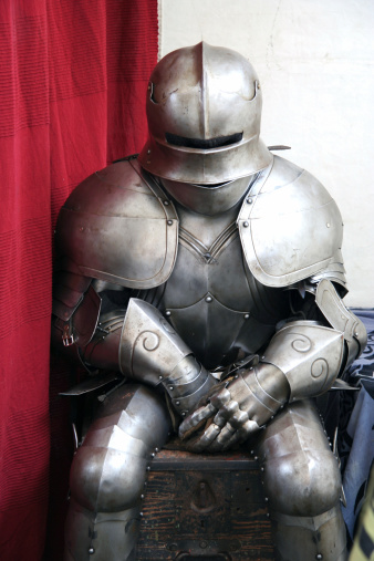 An empty knight's armor sitting on a chest.
