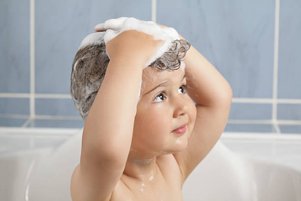 Small child washing hair in the tub stock photo