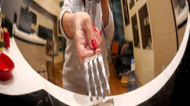 A reflection of a hand with a fork and a kitchen on a steel pot