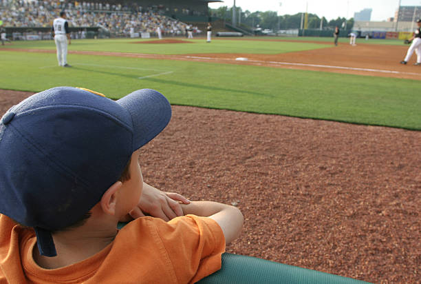 Little boy at baseball game dreams concept stock photo