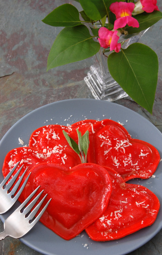 A plate of bright red heart-shaped ravioli ready for a couple to share.