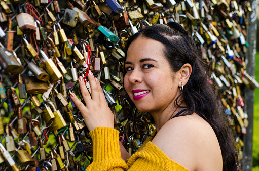 portrait of woman next to fence of love padlocks