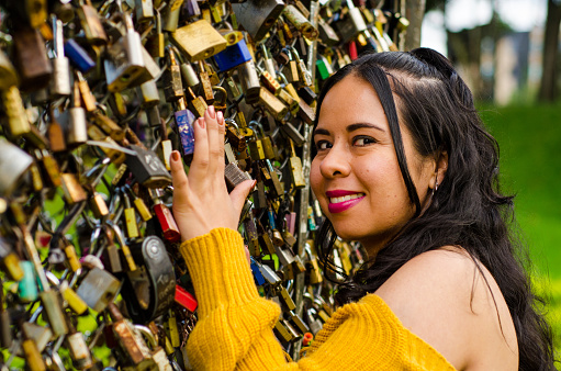 portrait of woman next to fence of love padlocks