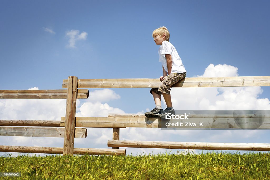 Chłopiec siedzi na Ogrodzenie - Zbiór zdjęć royalty-free (Ogrodzenie - Granica)