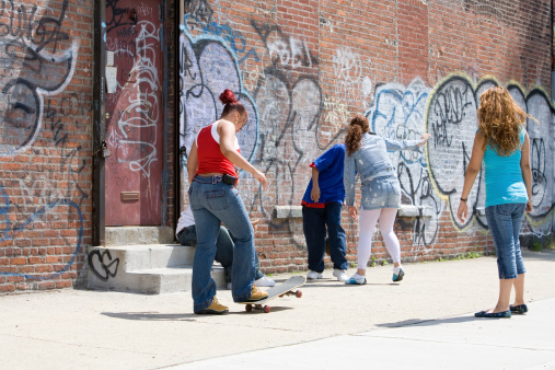 Diversified group of teenagers in a typical Brooklyn neighborhood. All with their back to the camera.