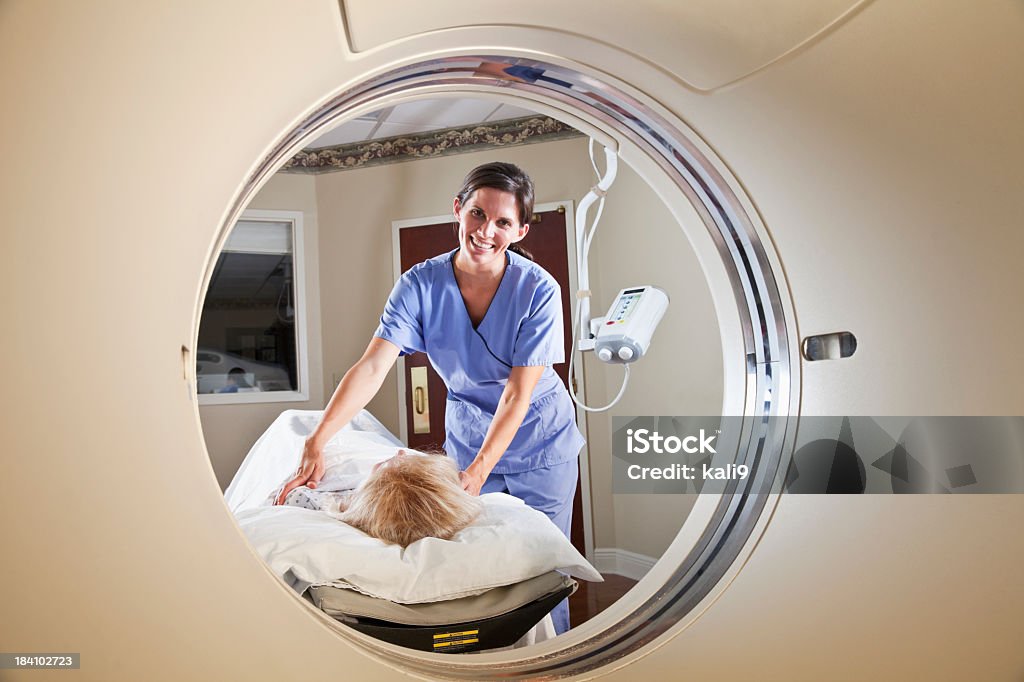 Healthcare worker preparing patient for CT scan Nurse or technician, 20s, with female patient, 50s, preparing for CT scan Covering Stock Photo