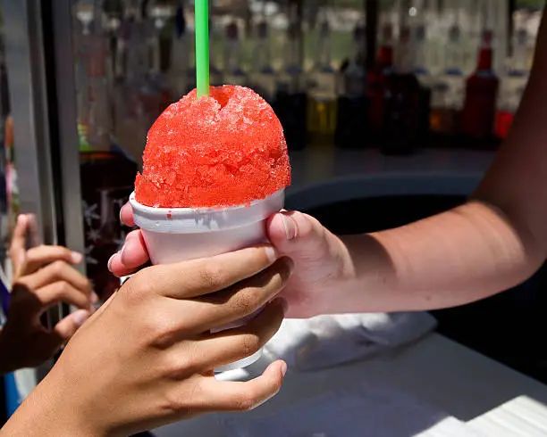 Young Girl is getting a snow cone on a hot day for refreshment.