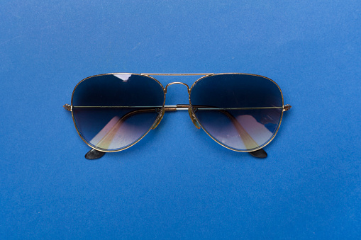 Sunglasses on color background, top view.