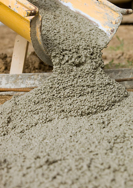 Wet concrete is pouring from a cement mixer trough into a sidewalk form at a residential construction site. The finished surface will be exposed aggregate which is the reason for the uniform large stones.\u2028http://www.banksphotos.com.c25.sitepreviewer.com/LightboxBanners/Concrete.jpg