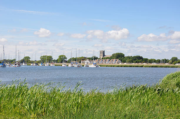 Christchurch in Dorset A view from Christchurch Harbour looking to the historic Priory. Boats in the water. Popular tourist destination and leisure area. christchurch england photos stock pictures, royalty-free photos & images
