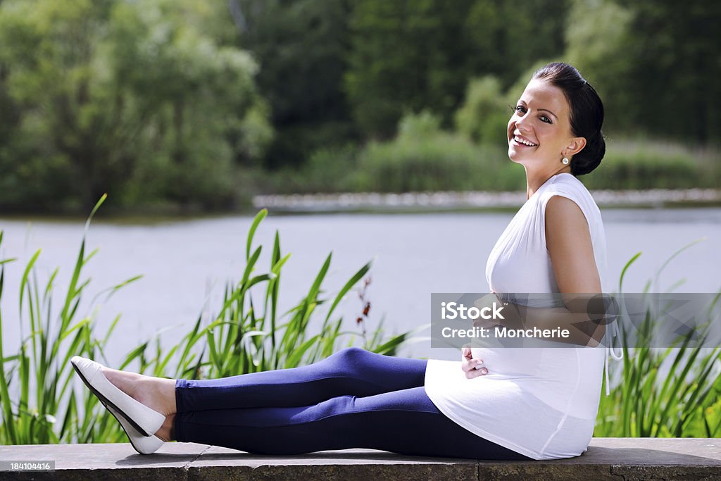 Jovem mulher grávida relaxante em um parque - Foto de stock de 20 Anos royalty-free