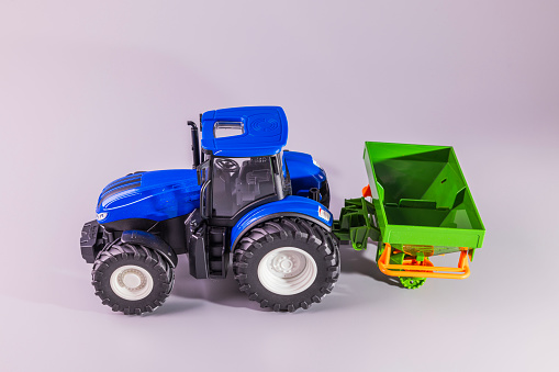 Close-up view of radio-controlled toy model of agricultural machinery isolated on gray background.