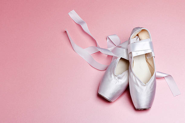 Well loved ballet pointe shoes. A pair of white pointe shoes on a pink background. ballet shoe stock pictures, royalty-free photos & images