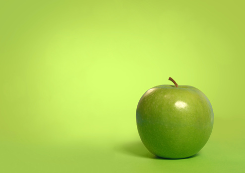 Green apple on a green background with space for text