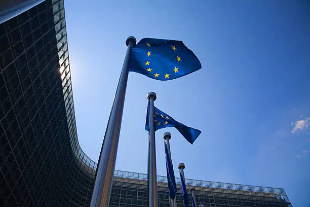 Series of European flags in front of the Berlaymont building in Brussels: the European Commission.