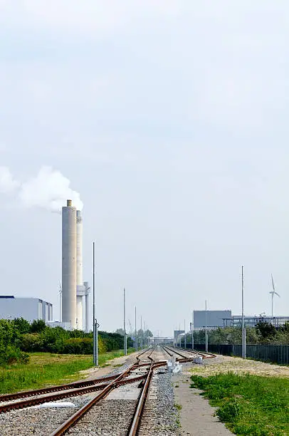 Railway tracks in a industrial area on an overcast day.