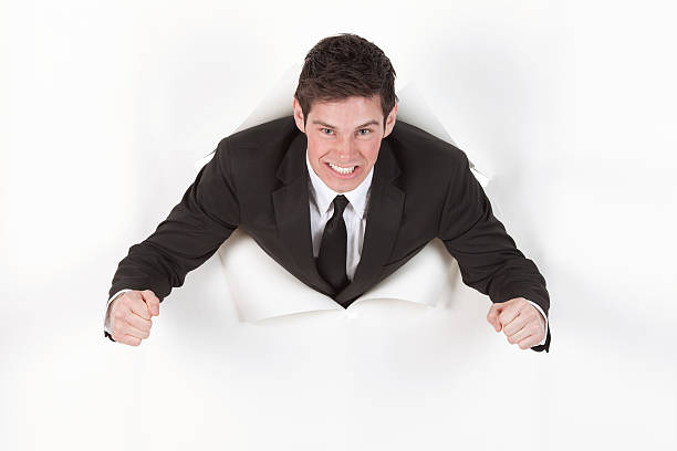 istock Aggressive businessman emerging through a hole in paper 184109104