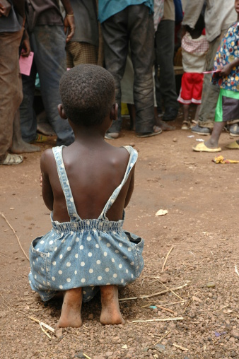 An African girl sits on the ground waiting for her turn for a vaccination.