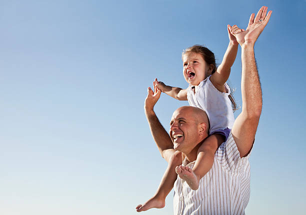 Father, 30s, and daughter, 2 years, reaching up to the sky