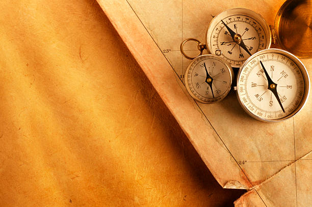 istock Three Compasses On Old Tattered Map Sitting On Golden Paper 184110532