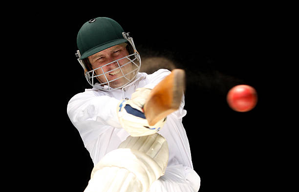 istock Make cricket player executing shot on red ball against black 184111100