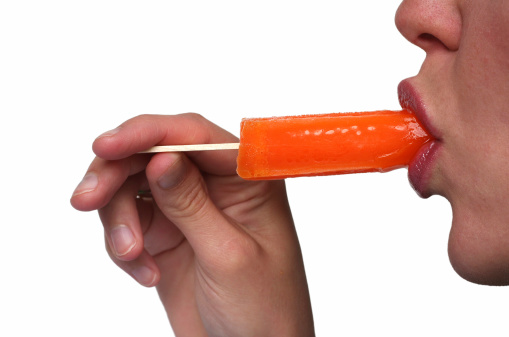 A young woman enjoying a nice cold orange popsicle isolated on white.