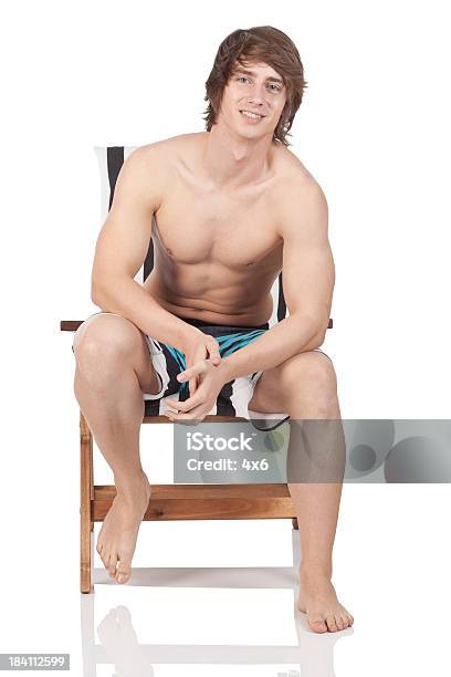 Foto de Musculoso Homem Sentado Em Uma Cadeira De Praia e mais fotos de stock de 20 Anos - 20 Anos, Adulto, Atividade Recreativa