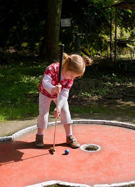 menina jogar o seu primeiro jogo do mini-golfe - little girls fun lifestyle handcarves imagens e fotografias de stock
