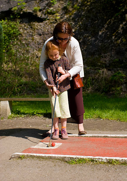 rapariga com a sua mãe, aprendendo a jogar mini-golfe - little girls fun lifestyle handcarves imagens e fotografias de stock