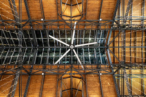 Wooden ceiling with large ceiling fan and gray structural steal members looking up.