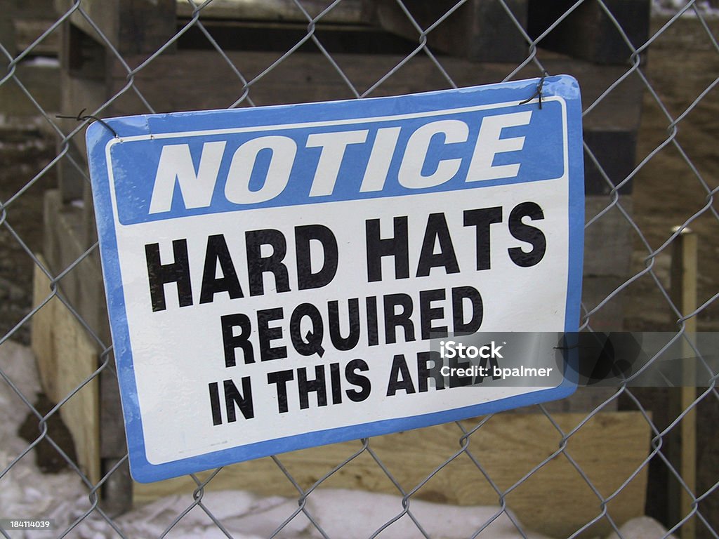 sign - Hard Hats Required Sign in front of a fenced off construction Bent Stock Photo