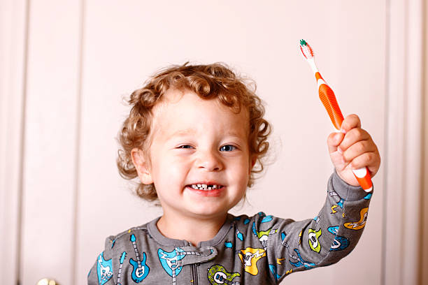Toddler holding toothbrush in air and smiling  stock photo