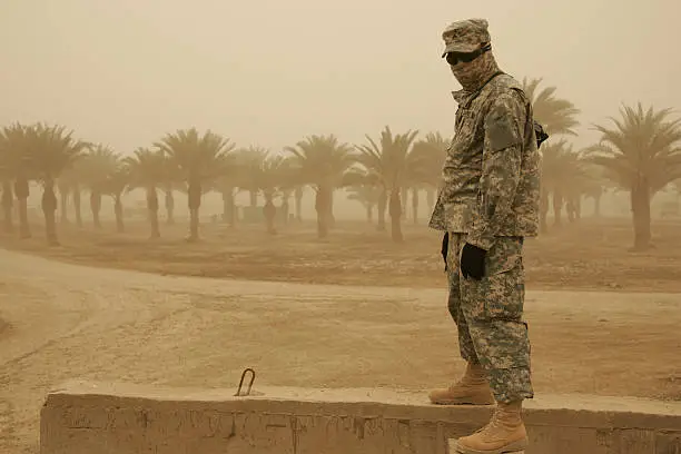 "A masked American soldier withstands a sandstorm in Baghdad, Iraq."