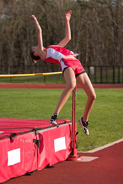 Lady High Jumper Lady high jumper in the air clearing the bar. school sport high up tall stock pictures, royalty-free photos & images