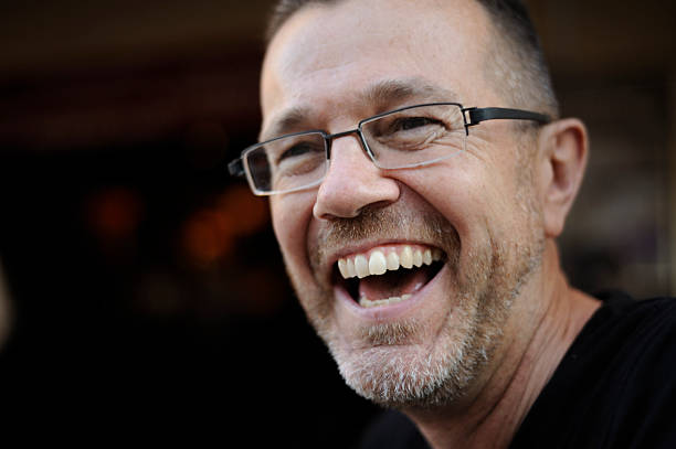 A mature man with glasses laughing out loud; he's having a great time.