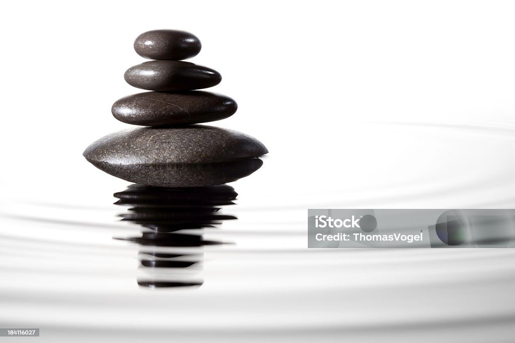 Balanced black stones in water - Feng Shui Massage Lastone Close up photograph of stacked black massage stones in water. ProPhoto color space.More like this: Water Stock Photo