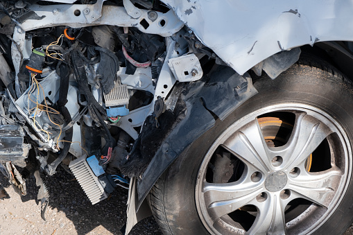 car after an accident, severed wires dangle from the front of damaged vehicle, illustrating the aftermath of the collision.