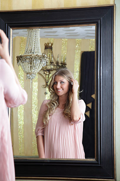 istock blond women looking in a mirror 184116616