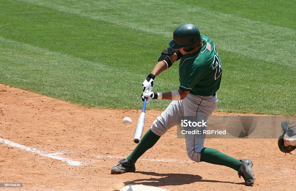 Baseball batter in green uniform hitting ball a baseball hitter Baseball - Sport Stock Photo