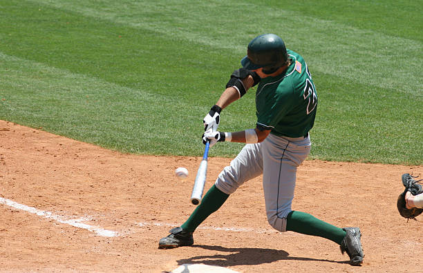 Baseball batter in green uniform hitting ball a baseball hitter batting sports activity photos stock pictures, royalty-free photos & images