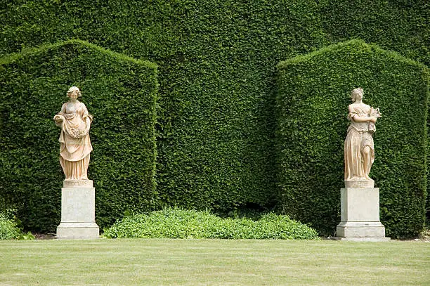 Photo of Two marble statues against hedges in an English garden