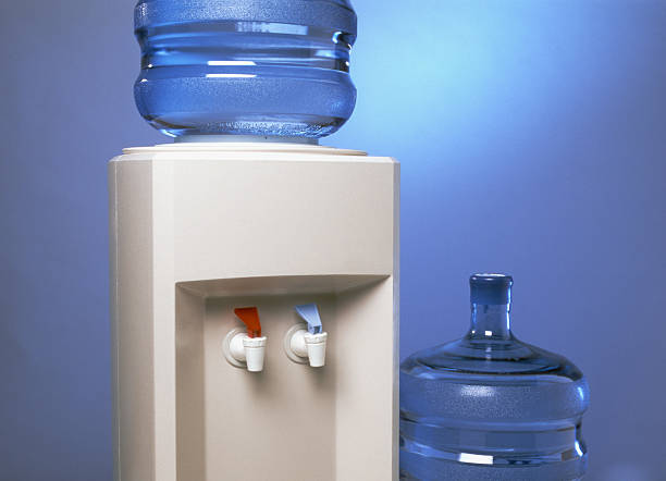 Close-up of water cooler/dispenser with large bottles.