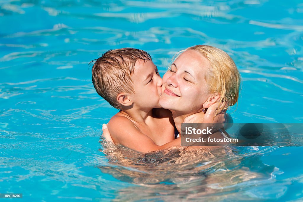 Petit garçon Embrasser sa mère au bord de la piscine - Photo de Piscine libre de droits