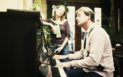 mature couple playing the piano, shoot with very shallow dof - focus on male model