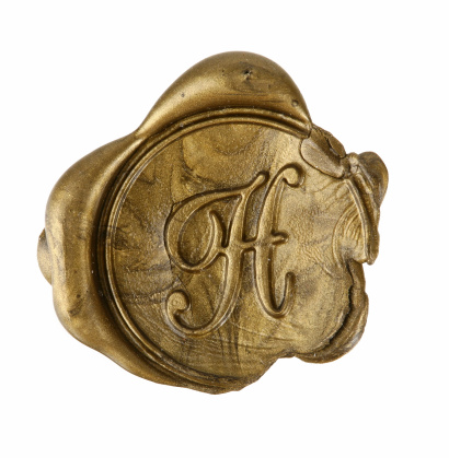 Macro photo of a gold wax seal with the letter H.