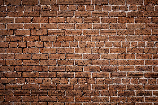 Background texture of a brown brick wall with white mortar.