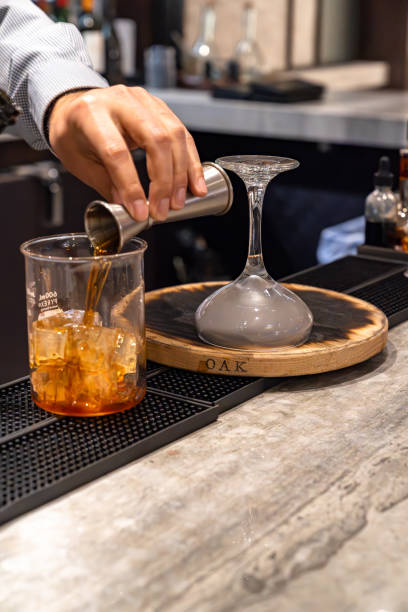 istock Bartender pouring whiskey out of a jigger and making smoked whiskey cocktail drink 1841201530